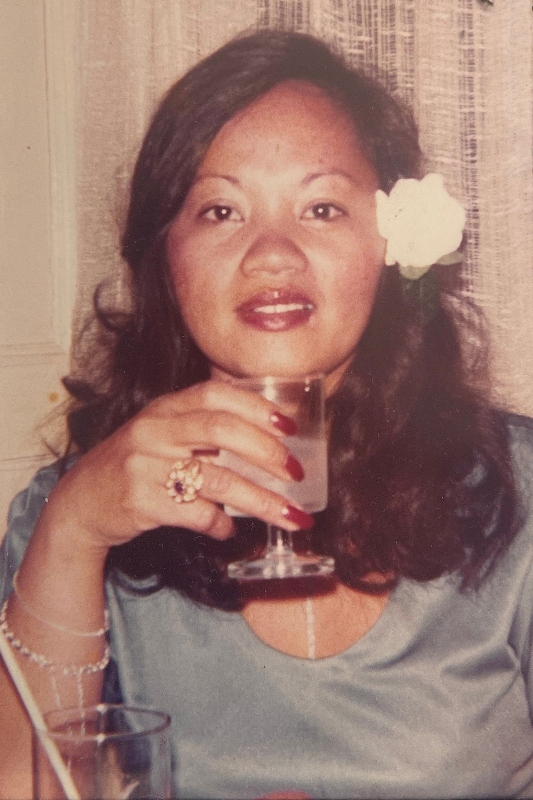 An image of a young woman with a flower in her hair, holding a glass