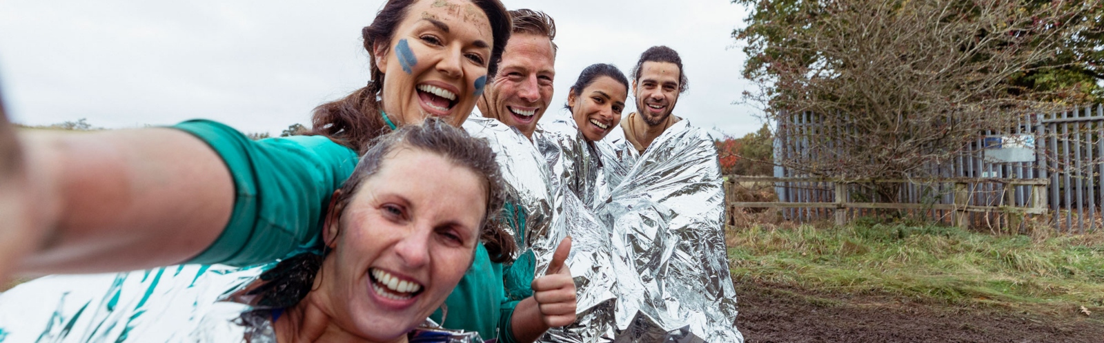 A group of friends wrapped in foil blankets after completing a charity challenge